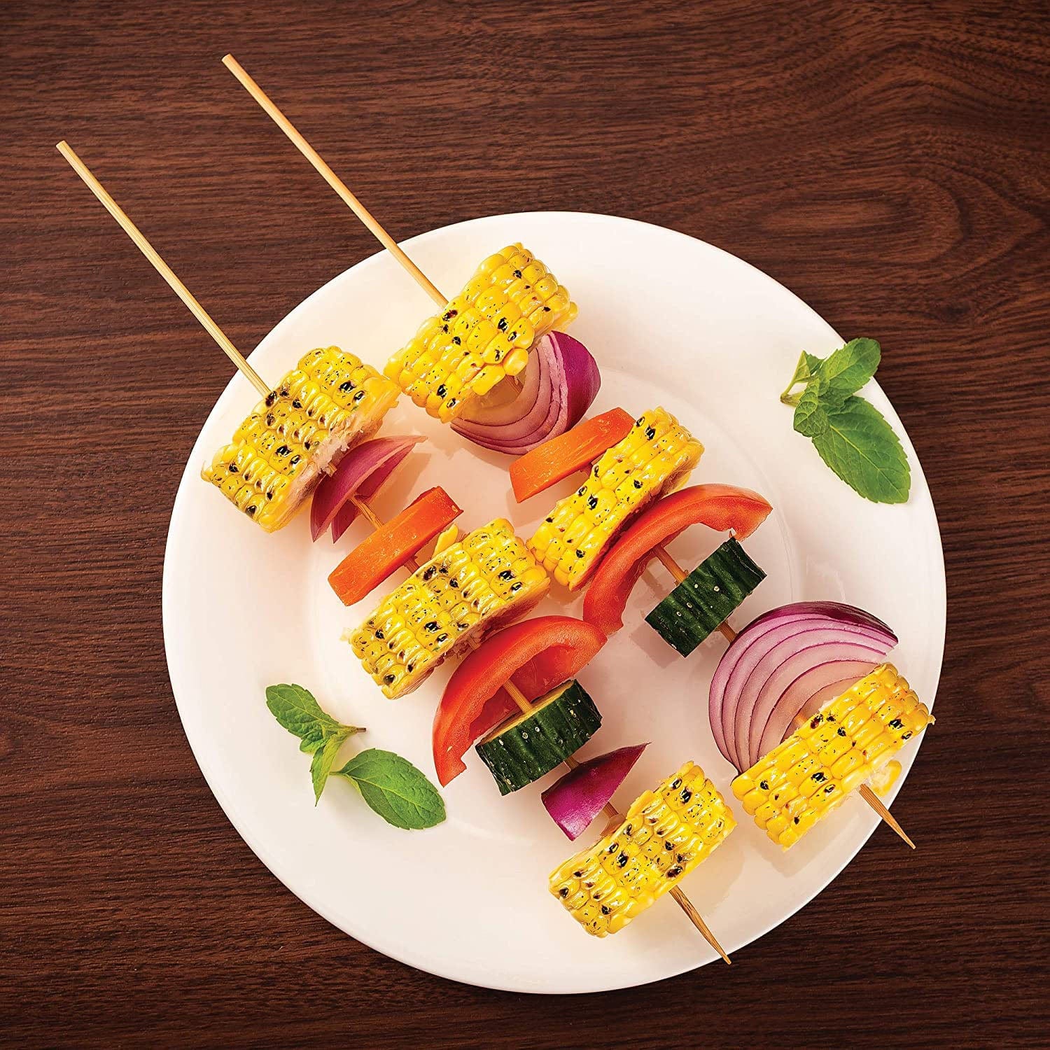 Two 12 natural light brown bamboo skewers piercing grilled vegetables on a white plate