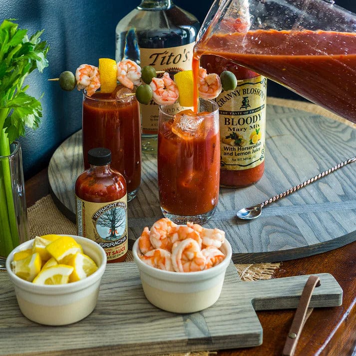 19 round ash wood serving board in gray with a leather accent holding Bloody Marys and garnish
