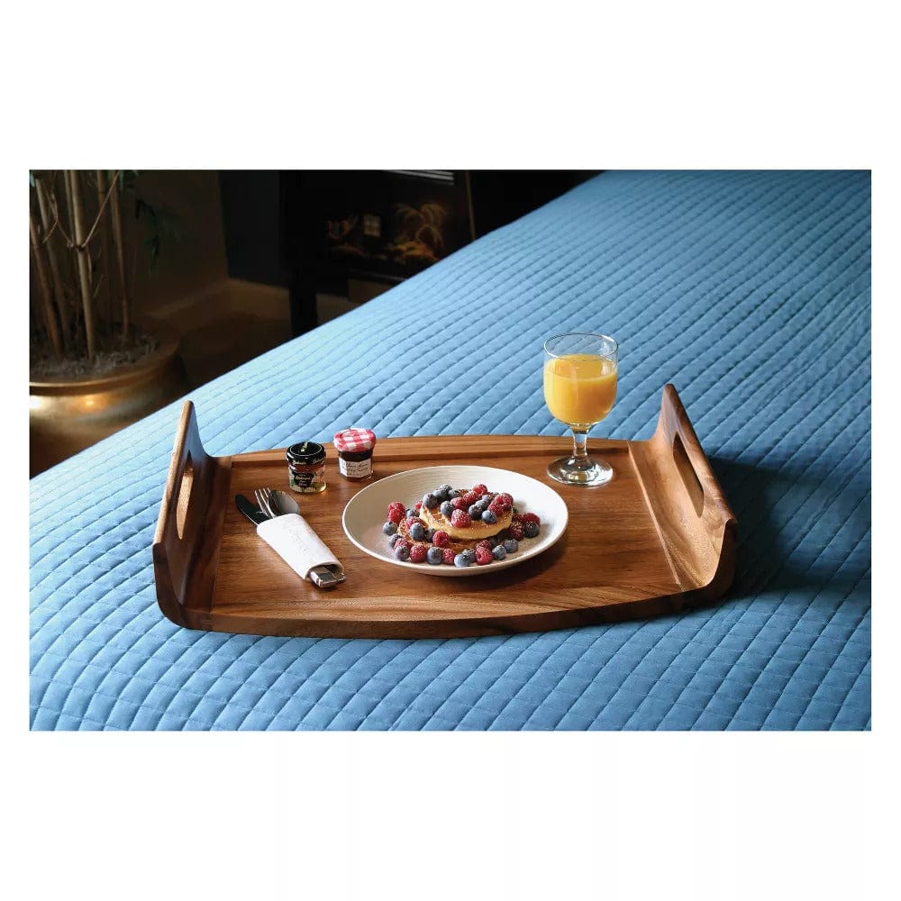 Reversible acacia wood serving bed tray with cutout handles holding breakfast on a blue quilted comforter