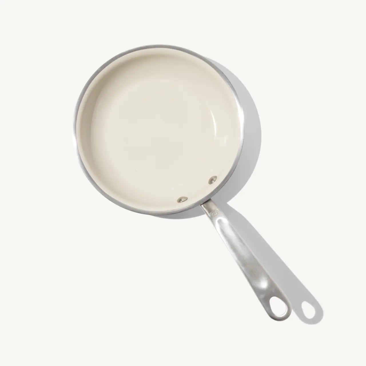 8 CeramiClad frying pan with a silver exterior light beige interior and a polished silver handle with two holes