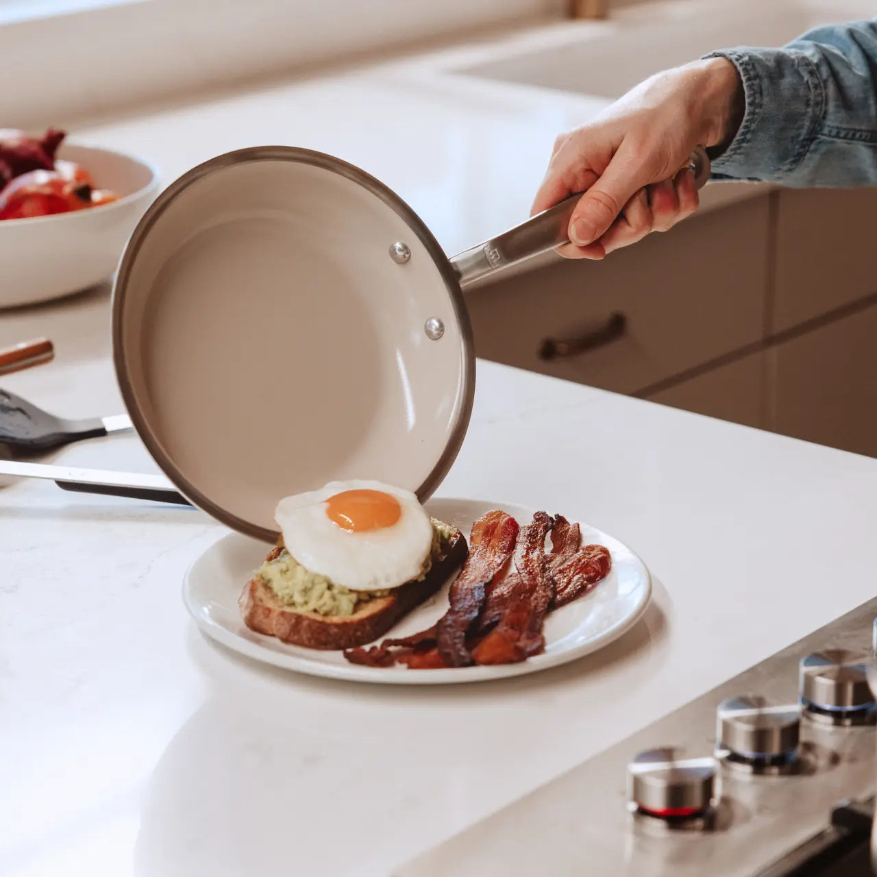 Persons hand holding a Made in Cookware 8 CeramiClad Frying Pan off-white interior over a plate