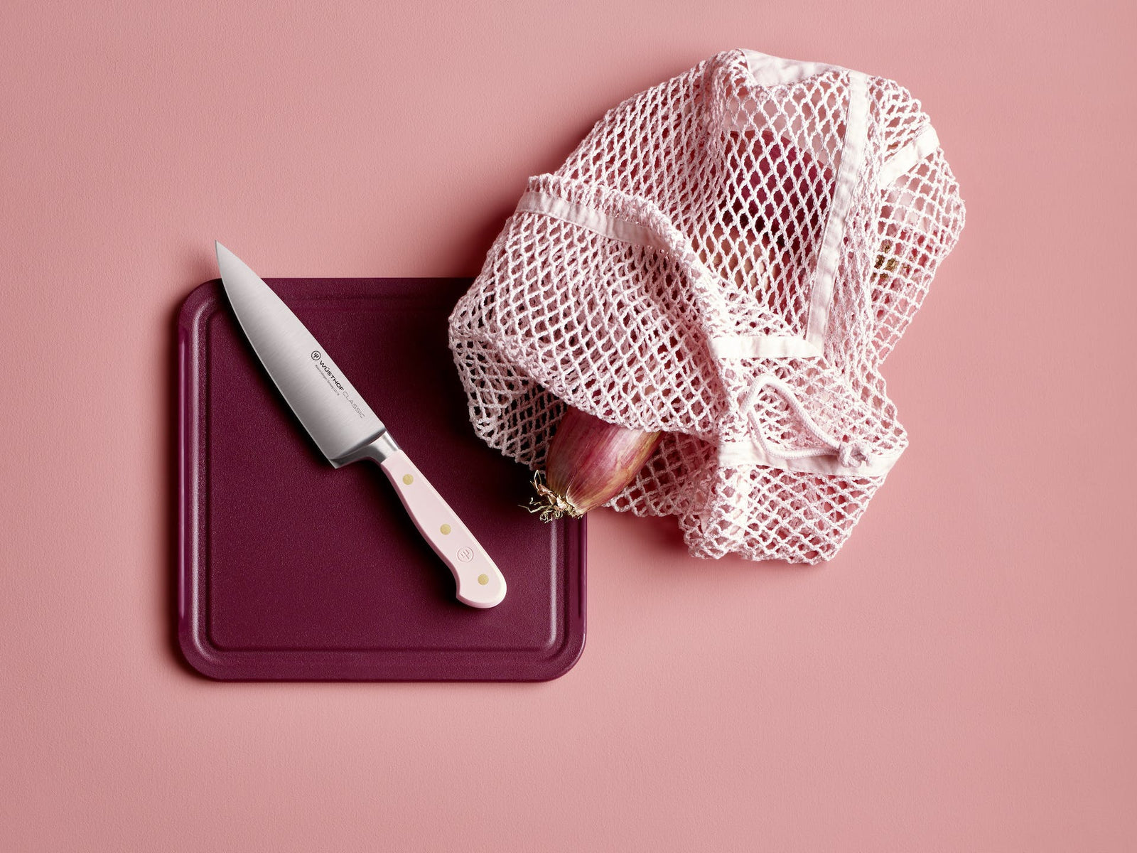Wusthof Classic 8 Chefs Knife with a pink handle lying on a purple cutting board