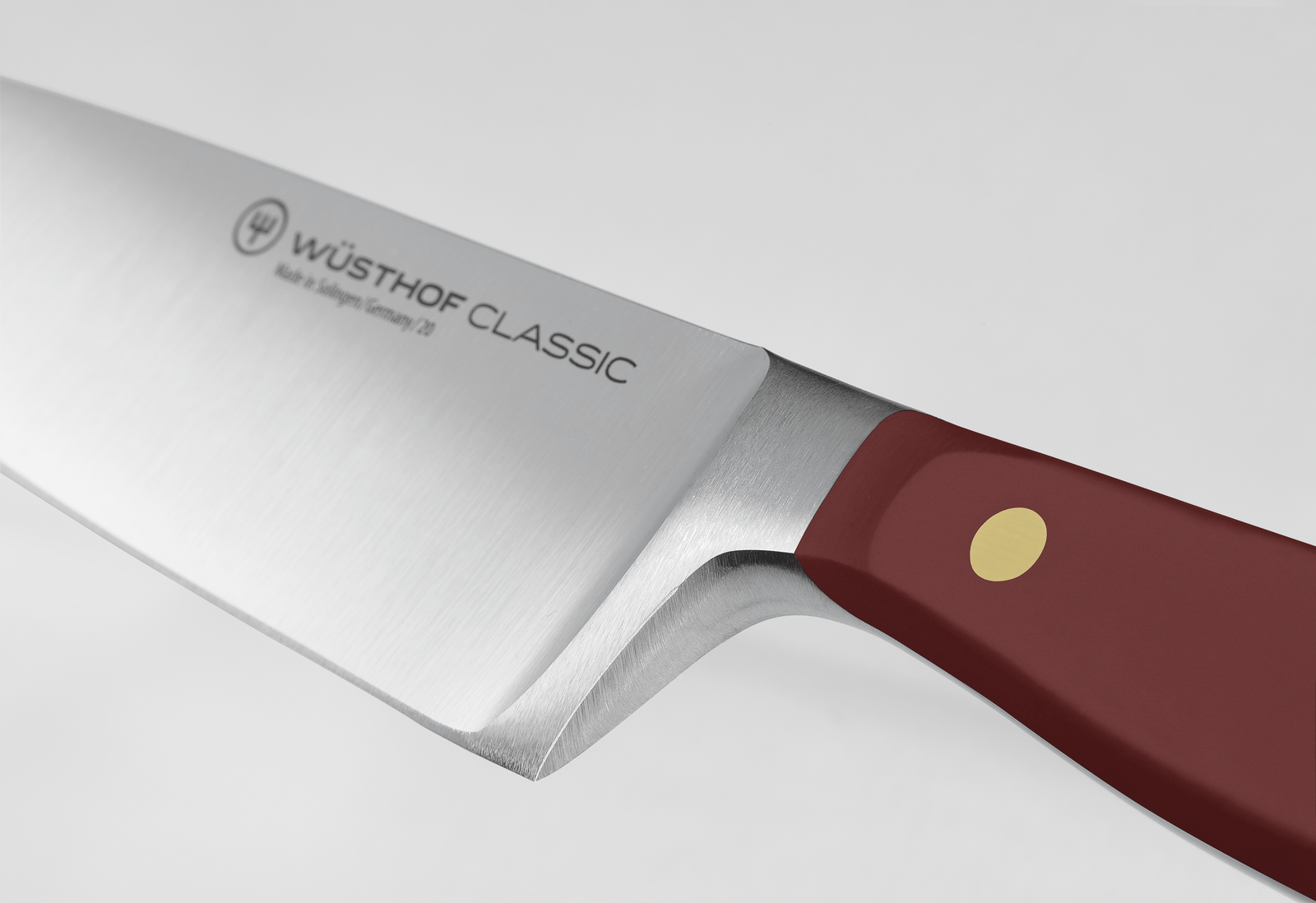Close-up of a Wusthof Classic 8 Chefs Knife with a silver blade and a dark red handle with one gold rivet