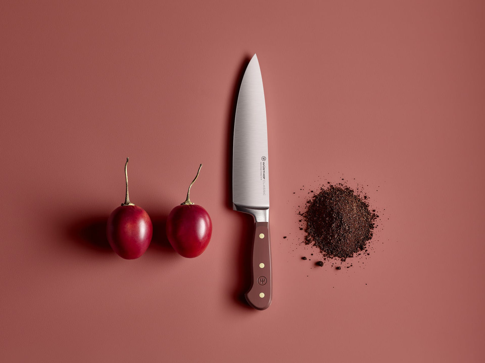 Wusthof Classic 8 Chefs Knife with a silver blade and reddish-brown handle next to two sumac fruits