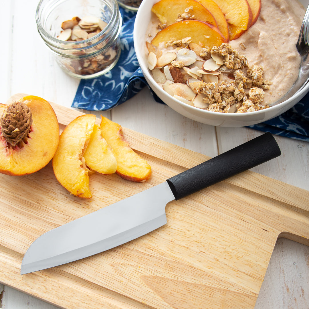 Zyliss 5-inch Santoku Knife with a black handle and stainless steel blade on a wooden cutting board