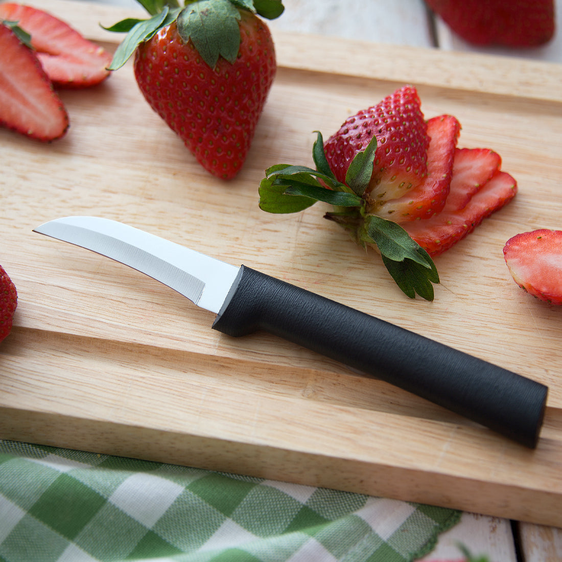 Stainless steel paring knife with black handle shown next to a partially peeled lime and lime zest