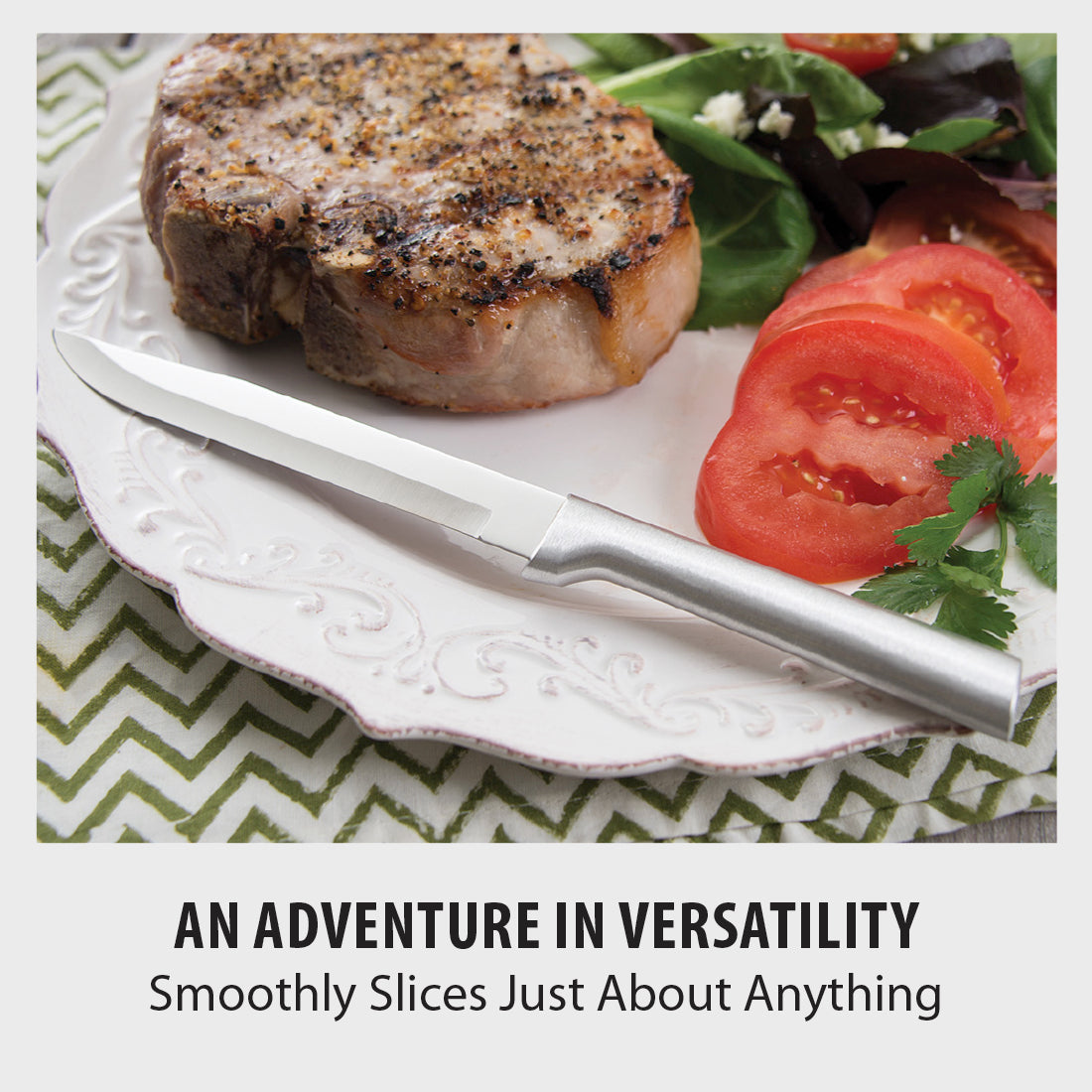 Stainless steel steak knife with a polished blade and a matte silver handle lying on a white dinner plate